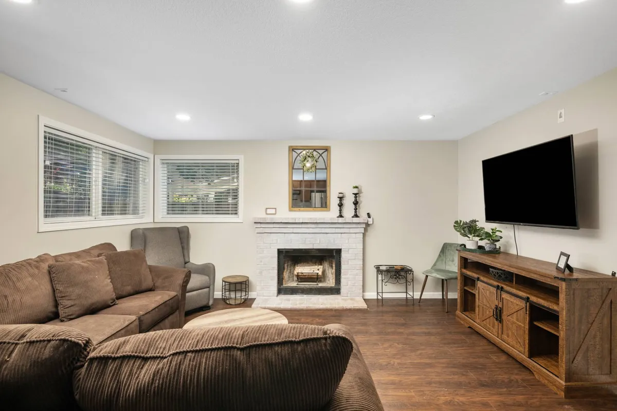 A modern, inviting living room with a plush sofa arranged around a cozy fireplace. The setup includes stylish decorative items and a wall-mounted TV, creating a comfortable space for relaxation, entertainment, and socializing.