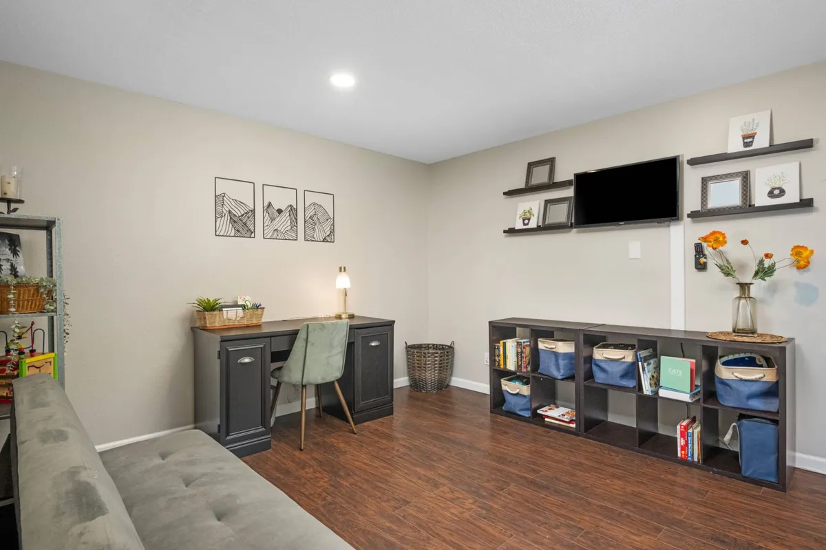 A calm and productive corner featuring a desk with a lamp, bookshelf, sofa, and thoughtfully arranged wall art. The scene is set for reading, quiet reflection, or focused work, with a soft, peaceful ambiance.