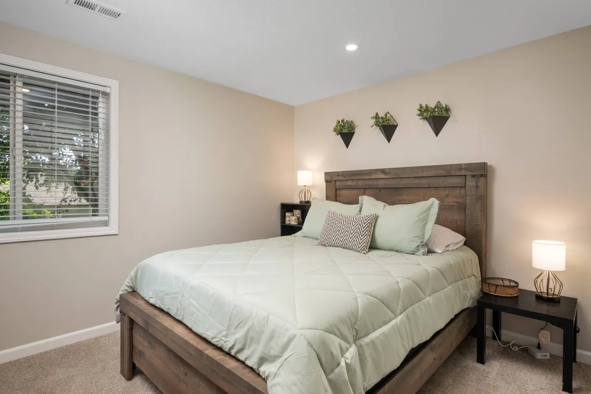 A tranquil bedroom setup with a bed, decorative wall planters, and a cozy nightstand with a lamp, exuding restful calm and a space conducive to both relaxation and quiet moments of productivity.